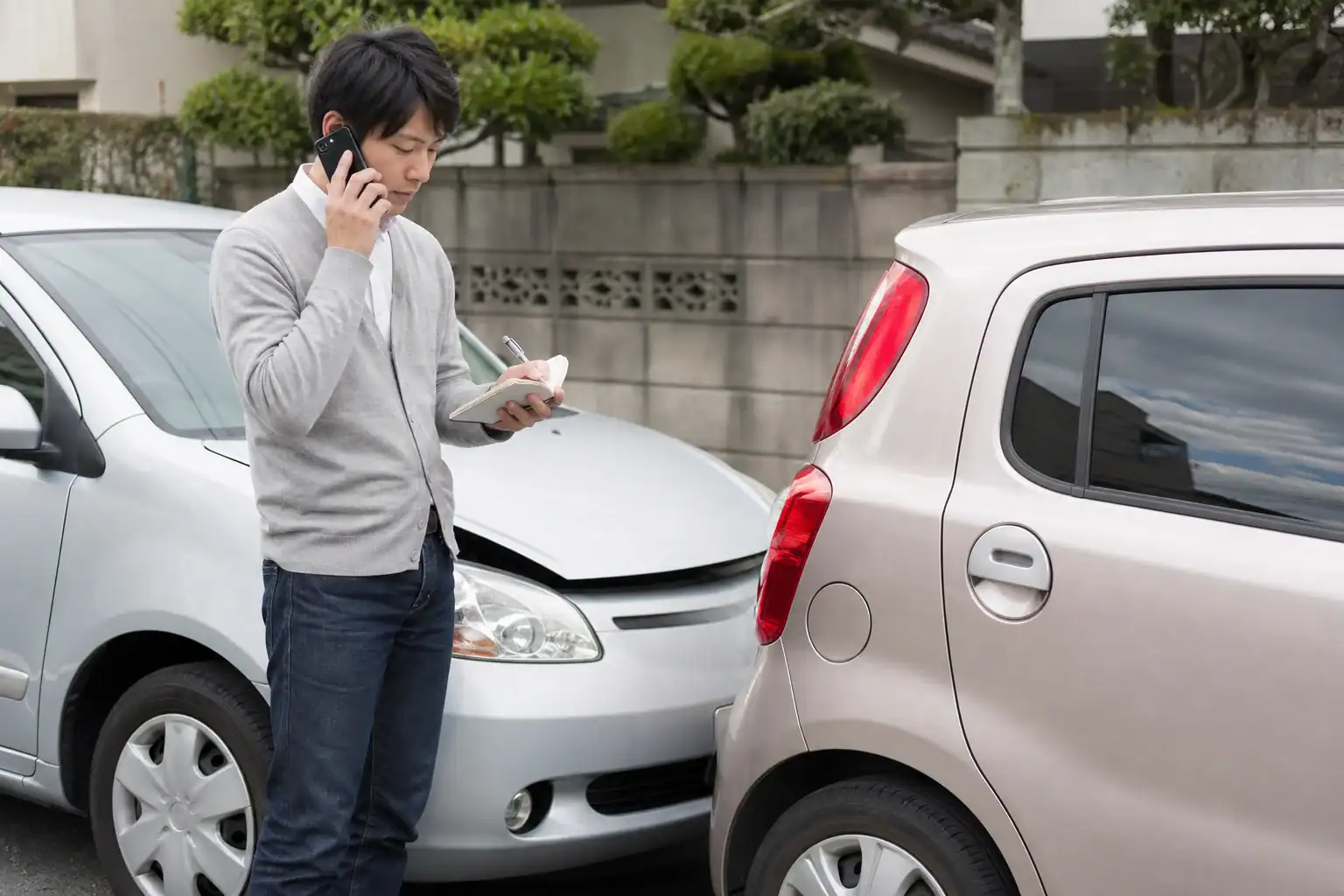 事故後に保険会社へ連絡しながら状況を記録するドライバー